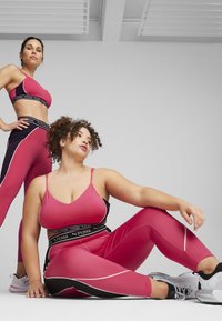 Sujetadores deportivos rosas y mallas con acentos en negro y blanco. Las mallas tienen una cintura alta y un diseño ajustado. Material suave y elástico.