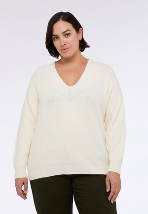 Maglione color crema, con trama a rilievo, scollo a V, maniche lunghe e vestibilità morbida. Presenta dettagli lavorati a maglia lungo lo scollo e l'orlo.