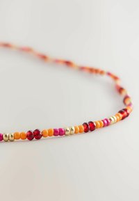 Colorful beaded necklace featuring orange, pink, red, and gold beads in various shapes, with smooth and faceted textures.