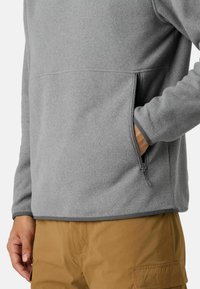Szary polarowy sweter z półsuwnym zamkiem błyskawicznym i boczną kieszenią, gładka tekstura oraz kontrastujące ciemniejsze wykończenia przy mankietach i dolnej krawędzi.