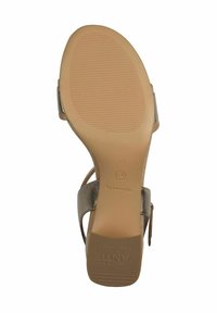 Semelle en caoutchouc beige d'une sandale avec une texture antidérapante, dotée d'une sangle métallique argentée et d'une boucle ajustable pour un maintien sécurisé.