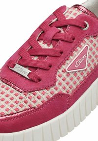 Baskets rose et crème avec une tige en tissu texturé, présentant un motif à damiers, des accents en daim, un logo en métal et une semelle blanche épaisse.