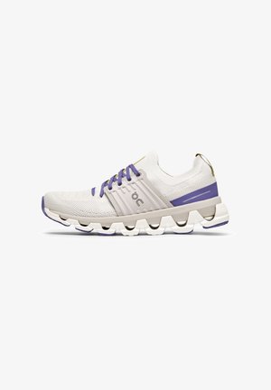 Baskets légères blanches avec un dessus en maille respirante, des accents violets et une semelle rembourrée ornée de motifs circulaires creux.