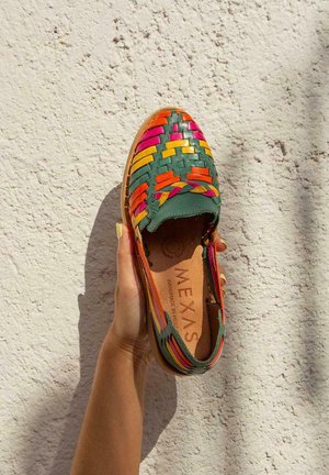 Zapato de lona colorido tipo slip-on con una base verde. Presenta acentos en naranja brillante, rosa y amarillo. Material de cuero con un interior beige.