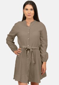 Vestito camicia in un morbido colore taupe, realizzato in tessuto texturizzato. Presenta maniche lunghe, una cintura da annodare in vita e cinque bottoni sul davanti.