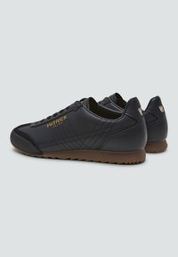 Zapatillas de cuero navy con una punta de negro texturizado, suela de goma marrón y logo dorado "PATRICK"; cuenta con costuras diagonales en los laterales.