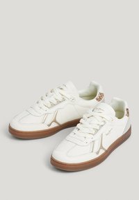 Sneakers bianchi in pelle con finitura liscia, suola in gomma marrone chiaro, dettagli dorati sul tallone e lacci bianchi.