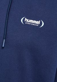 Marinblå hoodie i mjukt tyg med dragsko och en vit "hummel sportswear"-logotyp på bröstet.