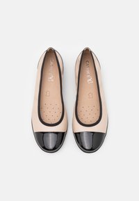 Beiga ballerinaskor med svarta lacktofflor och svarta detaljer, med perforerade innersulor och Caprice-logga på insidan.