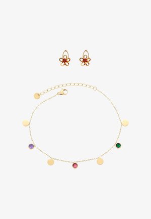 Arany lánc karkötő piros, zöld és lila drágakövekkel, valamint arany korong medálokkal, arany virág alakú fülbevalókkal párosítva, melyek piros köveket tartalmaznak.