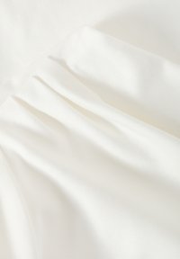 Bílá látka s hladkým povrchem, zdobená jemnými záhyby a subtilním leskem. Sestává z lehkého, pružného materiálu.