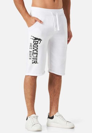 Shorts en coton blancs avec une taille élastique à cordon, poches latérales et texte noir imprimé sur la cuisse gauche. Texture lisse, design jusqu'au genou.
