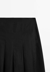 Zwarte geplooide rok met een gladde textuur, voorzien van gestructureerde panelen en een schone tailleband. De stof lijkt lichtgewicht en minimalistisch.