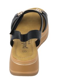 Sandales synthétiques noires avec une finition lisse, dotées d'un accent doré et d'une semelle intérieure rembourrée beige. Semelle légère avec plateforme et bords arrondis.