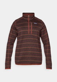 Sweater with a high collar, half-zip closure, features a red, black, and green zigzag pattern, made from textured knit fabric.