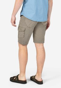 Khaki cargo shorts made of cotton blend, featuring side pockets, a relaxed fit, and a slightly frayed hem. Paired with dark slide sandals.