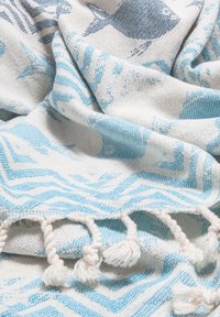 Soft woven fabric with blue and white fish and wave patterns, featuring twisted tassels along the edge.