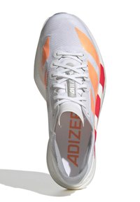 Bílé sportovní boty s oranžovými a červenými akcenty, texturovaným svrškem a plochými tkaničkami. Mají polstrovaný límec a minimalistický design.