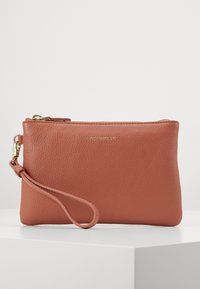 Porte-monnaie en cuir de couleur terra cotta atténuée, avec une surface texturée, des détails en métal doré et une fermeture éclair avec une sangle pour le poignet.