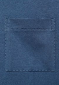 Niebieska bawełniana tkanina z małą kieszonką naszywaną, o gładkiej fakturze i widocznych szwach wzdłuż krawędzi. Prosty, funkcjonalny design.