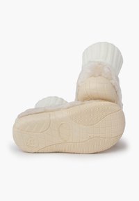 Pantofole color crema con una morbida parte superiore in pelliccia sintetica e risvolto in maglia a coste. La suola in gomma testurizzata presenta una presa con motivo per una migliore aderenza.