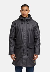Trench de lluvia gris impermeable con capucha, que cuenta con un cierre frontal, cordones ajustables y dos grandes bolsillos frontales. Textura suave y brillante.