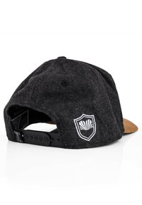 Cappellino da baseball in feltro nero con visiera marrone, dotato di un logo a scudo ricamato bianco sul retro e di una fasciatura regolabile in plastica.
