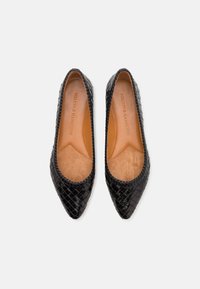 Ballerine in pelle intrecciata nera con punte appuntite e un morbido interno beige. Presenta una superficie testurizzata e un design minimalista.