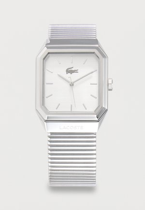 Silver Lacoste wristwatch with rectangular face, minimalist hour markers, and metal band with ridged texture.