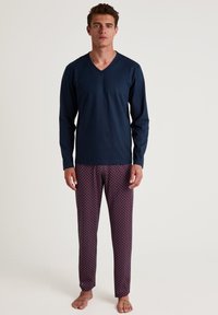 Navy long-sleeve V-neck top with matching burgundy pajama pants featuring a small white geometric pattern. Cotton material, relaxed fit.