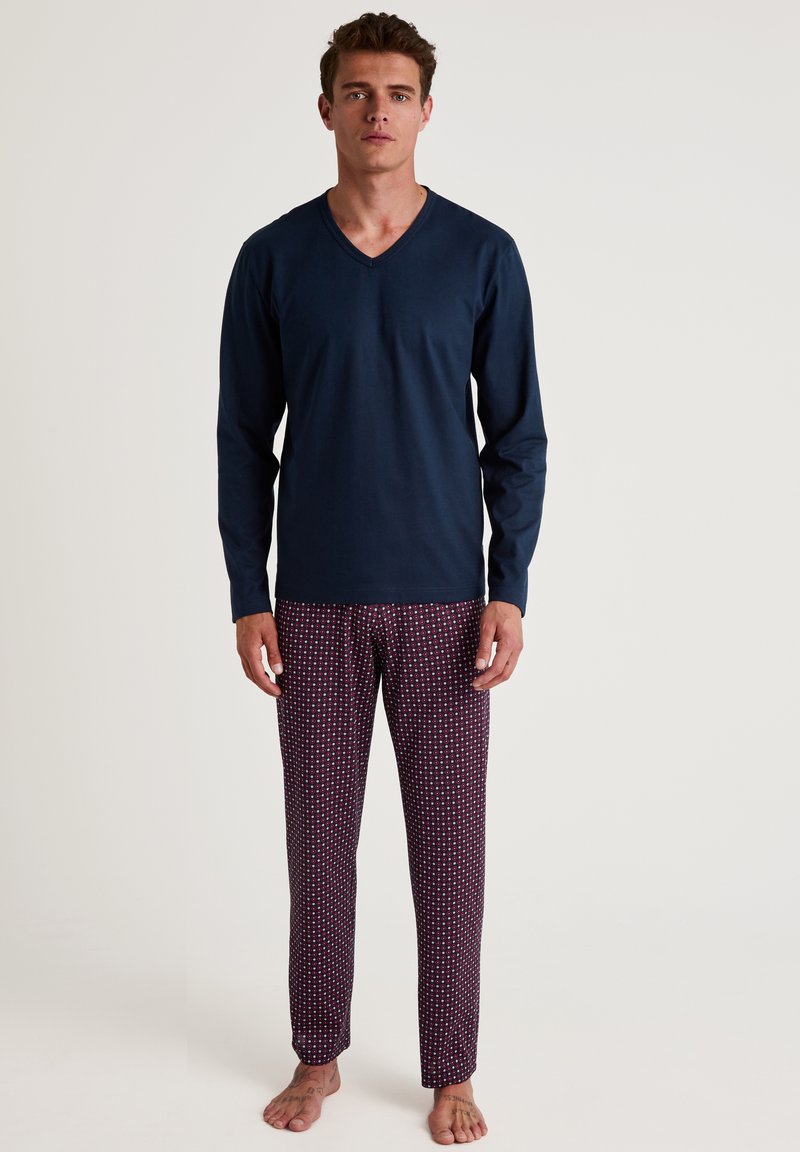 Navy long-sleeve V-neck top with matching burgundy pajama pants featuring a small white geometric pattern. Cotton material, relaxed fit.