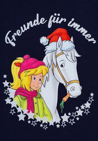 Il tessuto blu navy presenta una ragazza dei cartoni animati con un cappello e una sciarpa rosa accanto a un cavallo bianco che indossa un cappello di Babbo Natale rosso, con il testo "Freunde für immer" e stelle.