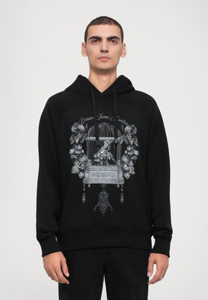 Schwarzer Hoodie aus weichem Stoff, mit einem detaillierten silbernen Grafikdesign eines Vogelkäfigs und Blumen auf der Vorderseite, mit einer Kapuze mit Kordelzug.