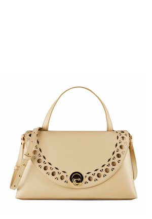 Sac à main en cuir beige avec poignée supérieure, bandoulière réglable, rabat festonné avec découpes circulaires et fermeture à verrouillage pivotant doré.