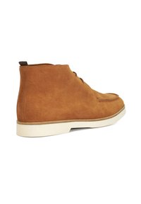 Brown suede ankle boots with white rubber soles, featuring a round toe, lace-up front, and a loop tab at the back.