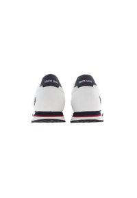 Scarpe da ginnastica bianche con un tallone blu navy, strisce di accento rosse e blu, e testo "SINCE 1890" sul retro. Suola in gomma resistente.