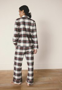 Rutet pyjamasæt i hvid, rød og sort, med en langærmet button-up skjorte og brede bukser, lavet af blødt, letvægtsstof.