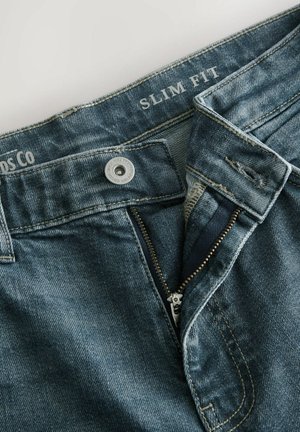 Blugi slim fit din denim albastru estompat, având închidere cu nasture metalic, fermoar cu accente aurii și detalii cusute pe talie.