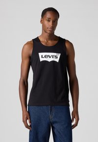 Débardeur noir en coton, avec un logo Levi's blanc sur la poitrine. Sans manches, encolure ronde et coupe décontractée.