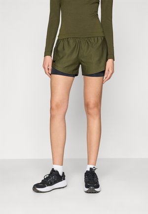Olivengrønne sportsshorts med elastisk talje, lagd over sorte indershorts, parret med sorte og hvide løbesko.