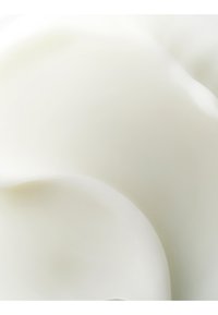 Gros plan d'une texture blanche, lisse et crémeuse avec des courbes douces, ressemblant à de la crème fouettée ou à un produit laitier similaire.
