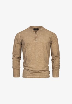 Camicia henley beige a maniche lunghe con scollo a v, tre bottoni in legno e un tessuto testurizzato con una leggera lucentezza.