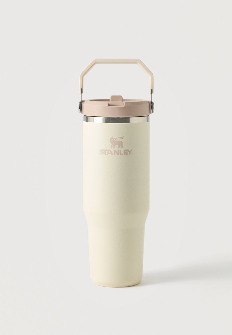 Magas krémszínű Stanley szigetelt bögre bézs tetővel és hozzáillő fogantyúval egy egyszerű fehér háttéren.