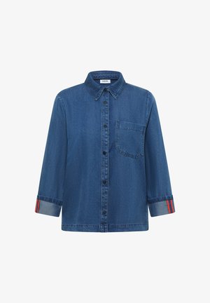 Camisa de mezclilla azul oscuro abotonada, con cuello, bolsillo en el pecho y puños doblados para mostrar un detalle de rayas rojas.