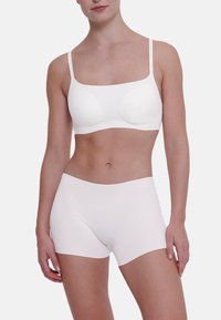 Seno bianco senza cuciture con leggera imbottitura e spalline regolabili, abbinato a un paio di mutande boyshort bianche, entrambi realizzati in tessuto morbido.