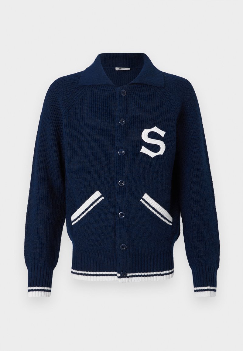 Navy gebreide cardigan met een kraag, knoopsluiting, witte gestreepte accenten op de zakken en manchetten, en een geborduurde 'S' op de borst.