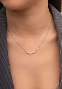 Collier en argent avec cinq pierres précieuses transparentes de tailles variées disposées dans un motif décoratif sur une chaîne délicate.