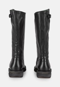 Bottes noires en cuir, arrivant au genou, avec une texture lisse, un bout arrondi et un petit talon empilé ; présentent un détail de boucle sur le côté.