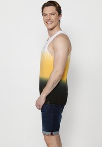 Meeste ilma käisteta gradient t-särk, millel on valged, kollased ja rohelise-musta tooni. Kombineeritud munakujuliste teksashortsidega. Sile puuvilla segu kangas.