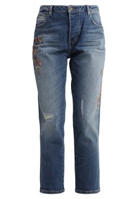 Vaaleansiniset farkut suoralla lahkeella, joissa on kukkakirjailu molemmilla etupuolilla ja kulutetut yksityiskohdat polvissa.